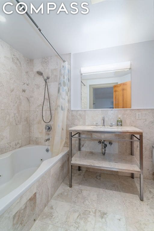 bathroom with sink, tile walls, and shower / bath combo with shower curtain