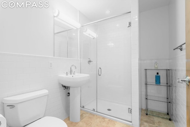 bathroom with a shower with shower door, tile walls, and toilet