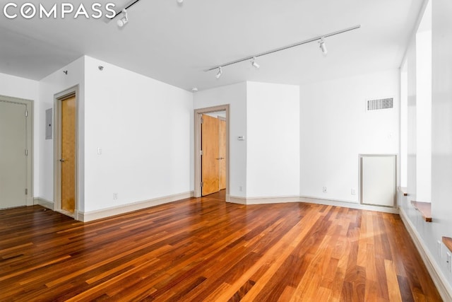 unfurnished room featuring wood-type flooring, electric panel, and track lighting