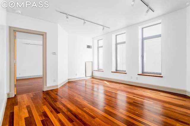 empty room with rail lighting and hardwood / wood-style floors