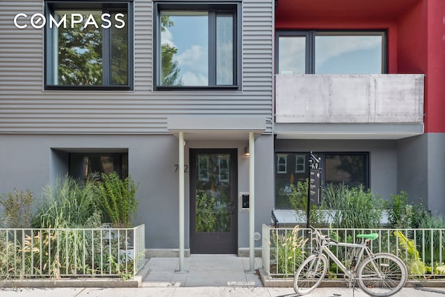 view of exterior entry featuring stucco siding and fence