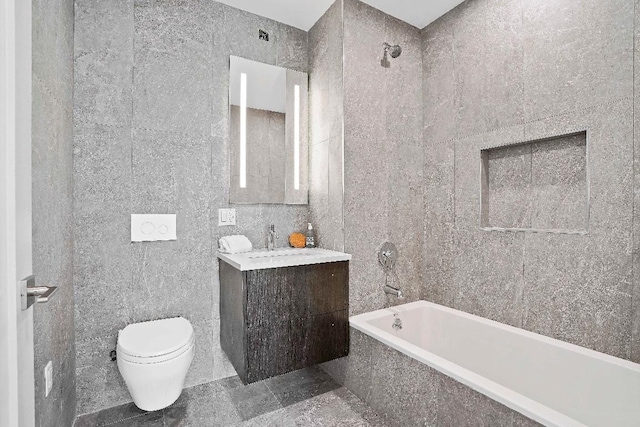 full bathroom with toilet, tile walls, tiled shower / bath, and vanity