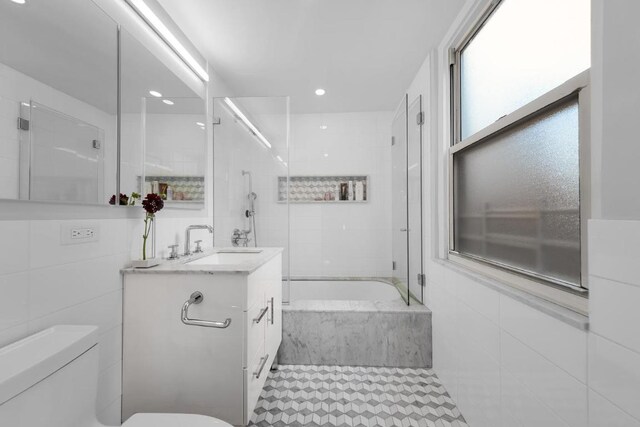 full bathroom featuring tile walls, tiled shower / bath combo, vanity, and toilet