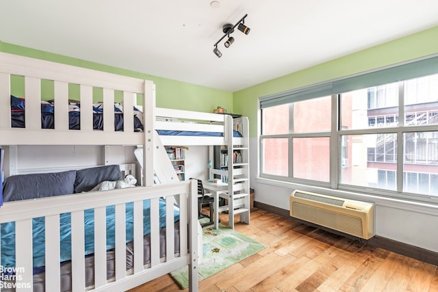 bedroom with light hardwood / wood-style floors and an AC wall unit