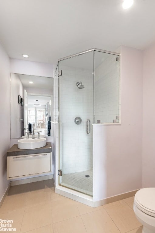 bathroom featuring toilet, walk in shower, vanity, and tile patterned flooring