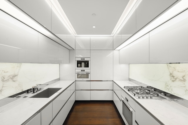 kitchen with sink, dark wood-type flooring, white cabinetry, light stone countertops, and stainless steel gas cooktop