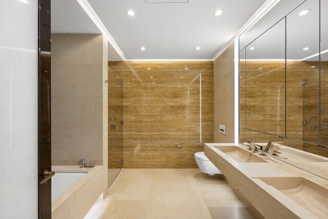 bathroom featuring tile walls, tile patterned flooring, ornamental molding, toilet, and tiled tub