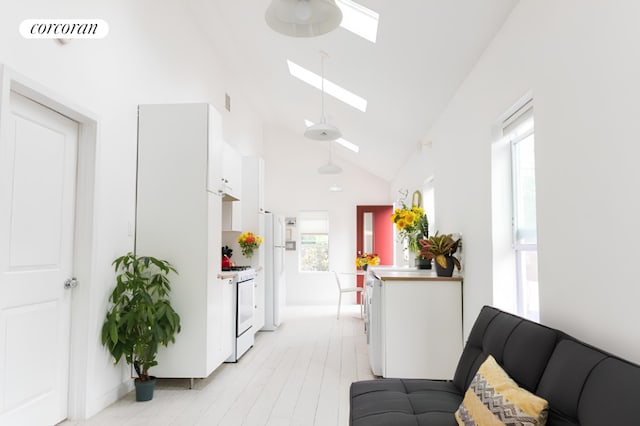 corridor with plenty of natural light, a skylight, high vaulted ceiling, and light hardwood / wood-style flooring