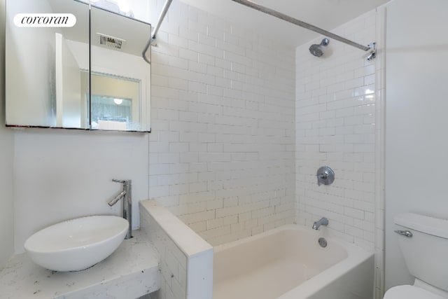 full bathroom featuring tiled shower / bath combo, sink, and toilet