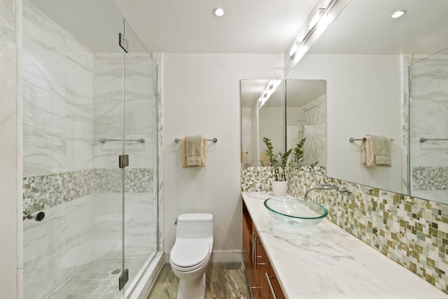 bathroom featuring tasteful backsplash, vanity, a shower with door, and toilet