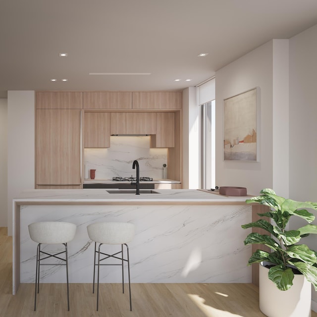 kitchen featuring a kitchen breakfast bar, modern cabinets, light brown cabinets, and light wood finished floors