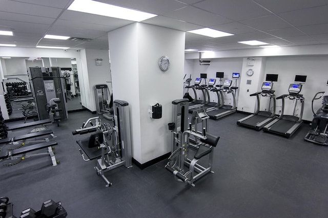 exercise room with a drop ceiling and baseboards