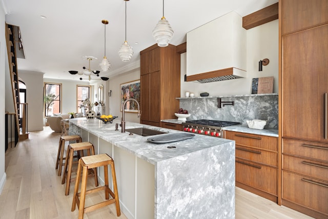 kitchen with a kitchen breakfast bar, pendant lighting, an island with sink, and sink