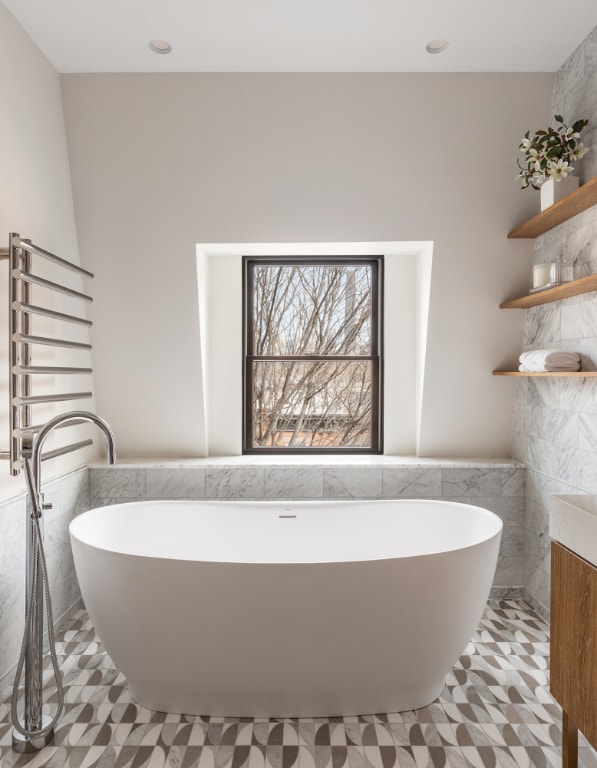 bathroom featuring tile walls, a tub to relax in, and radiator heating unit