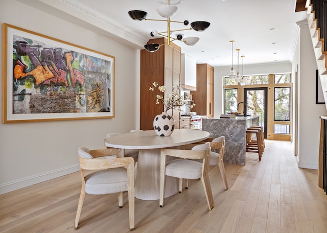 dining area featuring crown molding, light hardwood / wood-style flooring, and a notable chandelier