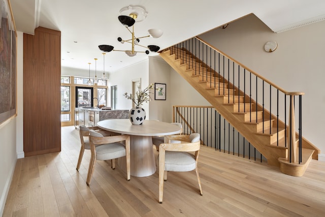 dining space featuring crown molding, light hardwood / wood-style floors, and a notable chandelier