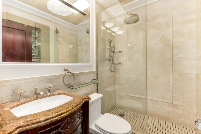 bathroom with toilet, vanity, tile walls, ornamental molding, and an enclosed shower