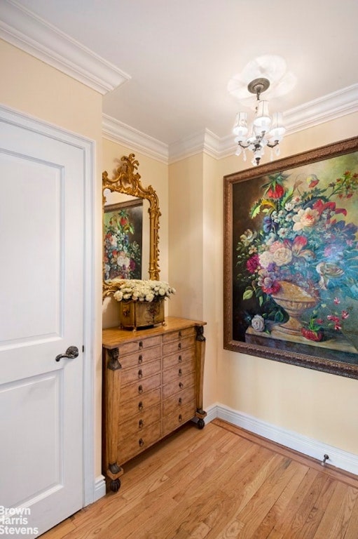 hall with ornamental molding, light hardwood / wood-style flooring, and a notable chandelier