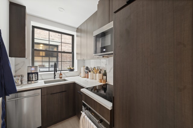 kitchen featuring sink, tasteful backsplash, dark brown cabinets, light hardwood / wood-style flooring, and stainless steel appliances