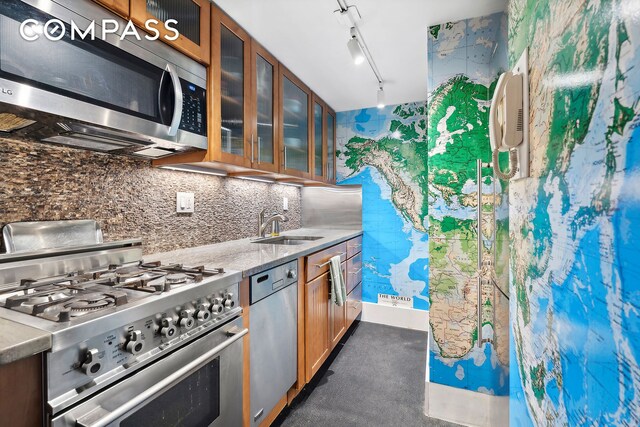 kitchen featuring backsplash, track lighting, stainless steel appliances, and sink