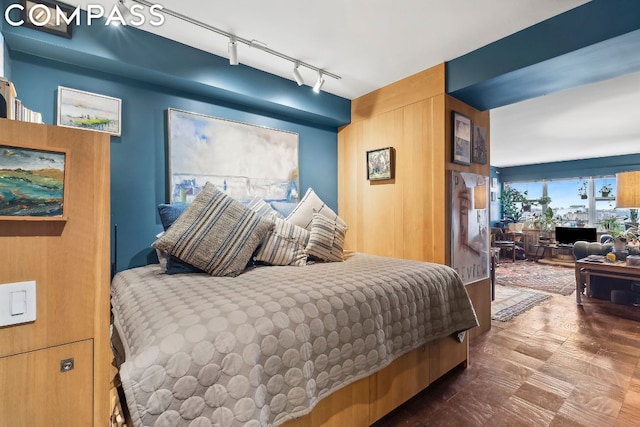 bedroom featuring track lighting and wood walls