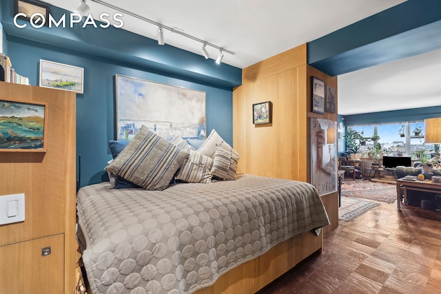 bedroom with rail lighting and wood walls