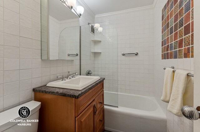 bathroom featuring toilet, bathing tub / shower combination, vanity, tile walls, and ornamental molding