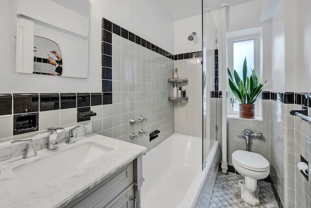 bathroom featuring toilet, bathing tub / shower combination, vanity, tile walls, and tile patterned floors