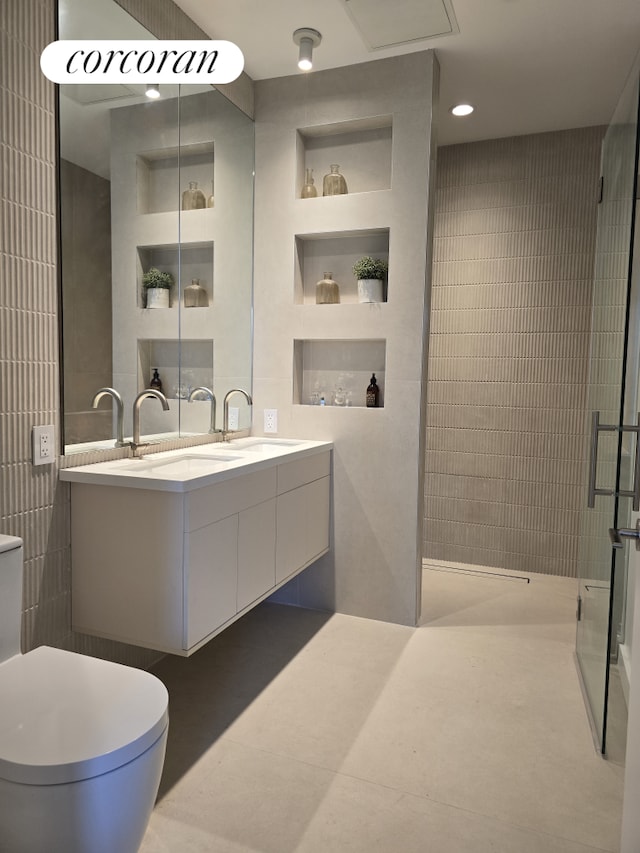 full bath featuring double vanity, a shower stall, toilet, and a sink