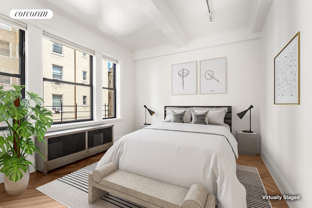 bedroom with rail lighting, radiator heating unit, and beam ceiling