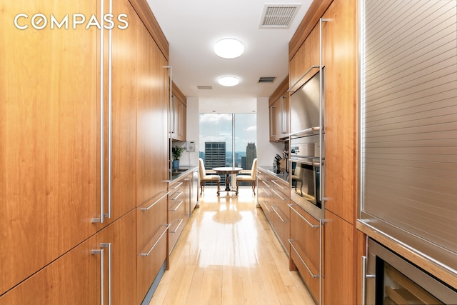 641 5th Ave Unit 49Cde, New York City, NY 10022 - kitchen with wine cooler, light wood finished floors, modern cabinets, floor to ceiling windows, and brown cabinetry