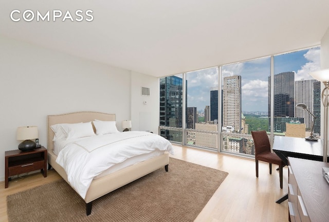 bedroom featuring access to outside, a wall of windows, and light hardwood / wood-style floors