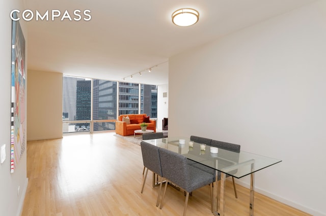 641 5th Ave Unit 49Cde, New York City, NY 10022 - dining space with light wood-type flooring, rail lighting, a wall of windows, and a city view