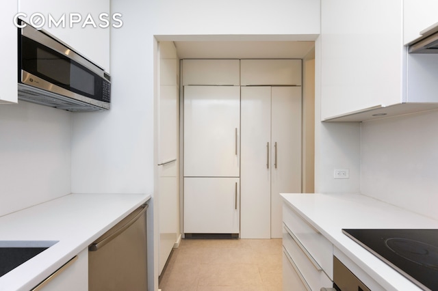 641 5th Ave Unit 49Cde, New York City, NY 10022 - kitchen with stainless steel microwave, light countertops, black electric cooktop, modern cabinets, and white cabinets
