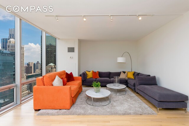 living room featuring expansive windows, rail lighting, and light hardwood / wood-style flooring