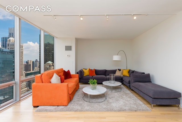 641 5th Ave Unit 49Cde, New York City, NY 10022 - living room featuring rail lighting, a skyline view, wood finished floors, and floor to ceiling windows