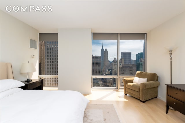 641 5th Ave Unit 49Cde, New York City, NY 10022 - bedroom featuring floor to ceiling windows, wood finished floors, and a view of skyline