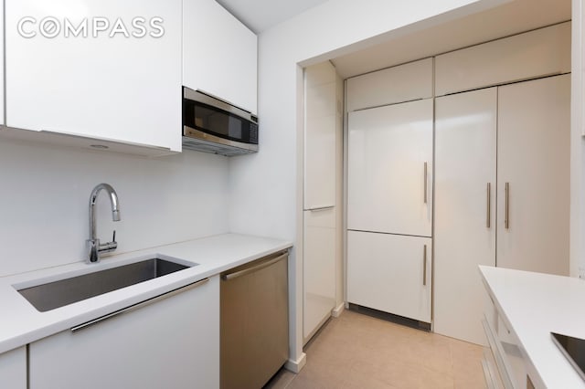 641 5th Ave Unit 49Cde, New York City, NY 10022 - kitchen with appliances with stainless steel finishes, white cabinetry, light countertops, and light tile patterned floors