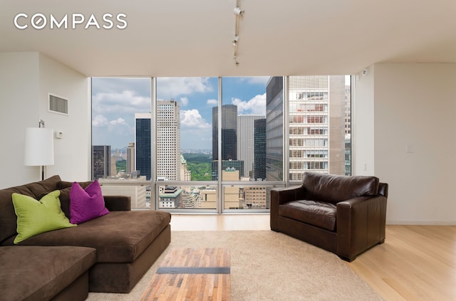 641 5th Ave Unit 49Cde, New York City, NY 10022 - living area with a view of city, wood finished floors, expansive windows, and track lighting