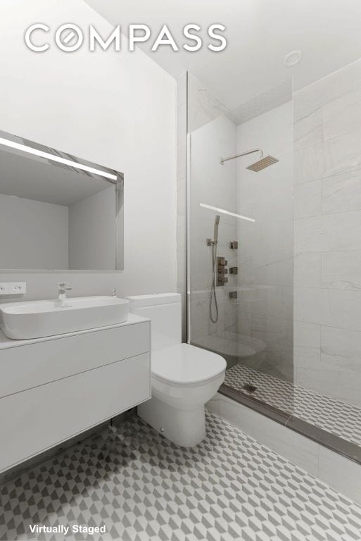 bathroom with vanity, toilet, and tiled shower