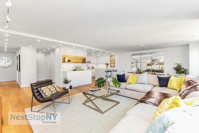 living area featuring baseboards, light wood-type flooring, and recessed lighting