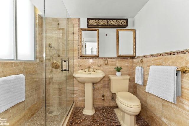 bathroom featuring tile patterned flooring, a shower stall, toilet, and tile walls