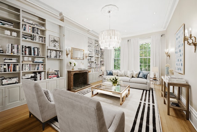 living room with ornamental molding, built in features, light hardwood / wood-style floors, and a chandelier