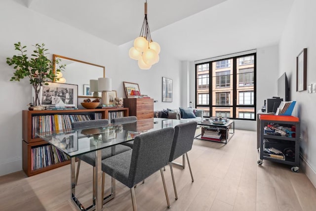 dining area with light hardwood / wood-style floors and a notable chandelier