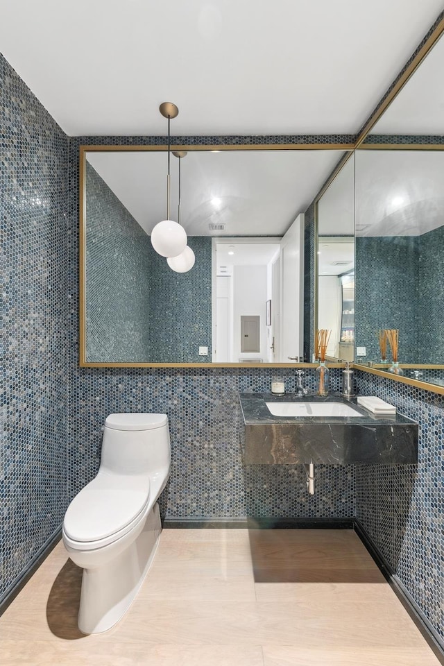 bathroom with a sink, toilet, and tile walls