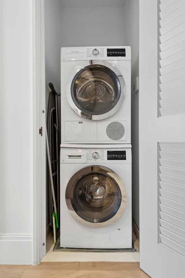 washroom featuring stacked washer and dryer, laundry area, and wood finished floors