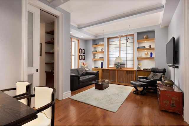 living area with built in shelves, hardwood / wood-style floors, and ornamental molding