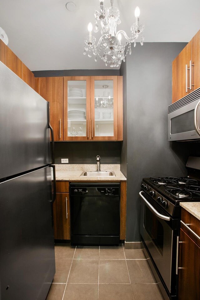 kitchen featuring light tile patterned flooring, sink, appliances with stainless steel finishes, pendant lighting, and light stone countertops