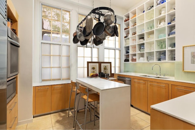 kitchen with sink, a wealth of natural light, light tile patterned floors, and a breakfast bar