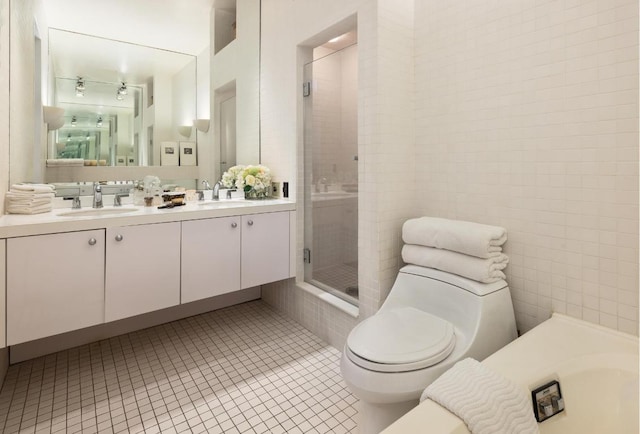 bathroom with tile patterned flooring, tile walls, vanity, a shower with shower door, and toilet